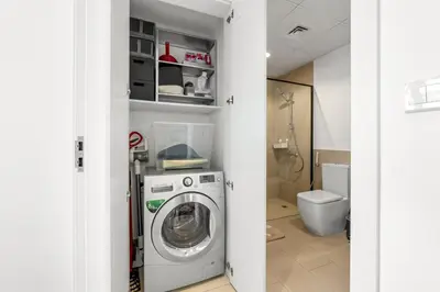 a bathroom with a washing machine and a toilet at Waves - Stylish Blue Haven near Town Square Park in Dubai