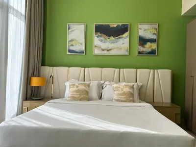 a bedroom with a large white bed with green walls at Bespoke Holiday Homes - Upscale 1BR Penthouse in Millenium Binghatti in Dubai