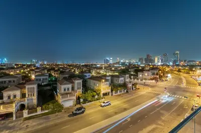 a city street at night with cars on the road at Bright 2BR Retreat Balcony & Pool Near Jumeirah Village Circle in Dubai