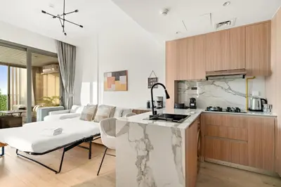 a kitchen and living room with a counter top at Bright 2BR Retreat Balcony & Pool Near Jumeirah Village Circle in Dubai