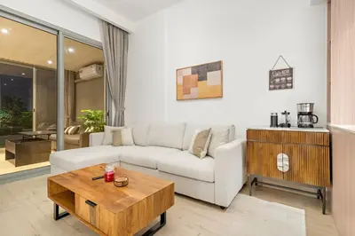 a living room with a white couch and a coffee table at Bright 2BR Retreat Balcony & Pool Near Jumeirah Village Circle in Dubai