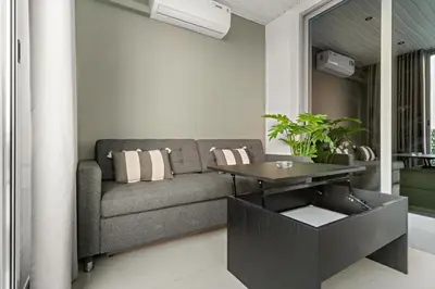 a living room with a couch and a table at Bright 2BR Retreat Balcony & Pool Near Jumeirah Village Circle in Dubai