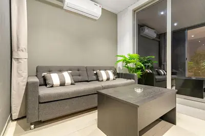 a living room with a couch and a table at Bright 2BR Retreat Balcony & Pool Near Jumeirah Village Circle in Dubai
