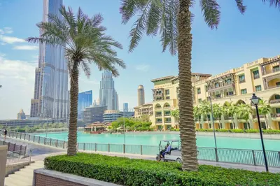 a golf cart parked between two palm trees in a city at The Fountain Views Suite in Downtown Dubai in Dubai