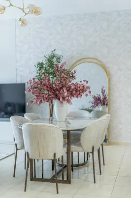 a dining room table with chairs and a vase with flowers at Nasma Luxury Stays - Sky-High Serenity in Stylish 2BR Retreat in Dubai