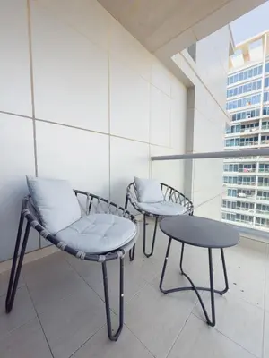 two chairs and a table in a room with a window at Nasma Luxury Stays - Sky-High Serenity in Stylish 2BR Retreat in Dubai