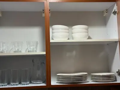 a cabinet filled with white plates and glasses at Livincci - Luxury Studio in Dubai Marina - 16 in Dubai