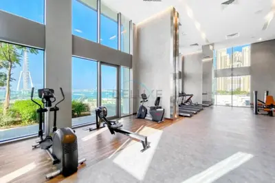 a gym with exercise equipment and large windows at Short walk to Marina Walk and JBR Beach, close to Bluewaters Island and Ain Dubai, 5242 Tower 1, Dubai Marina by Deluxe Holiday Homes in Dubai
