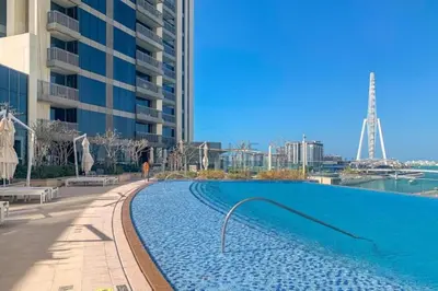 a large swimming pool next to a tall building at Short walk to Marina Walk and JBR Beach, close to Bluewaters Island and Ain Dubai, 5242 Tower 1, Dubai Marina by Deluxe Holiday Homes in Dubai