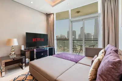 a bedroom with a bed and a tv and a window at Stylish 2BR - Near Burj Khalifa & City Views in Dubai