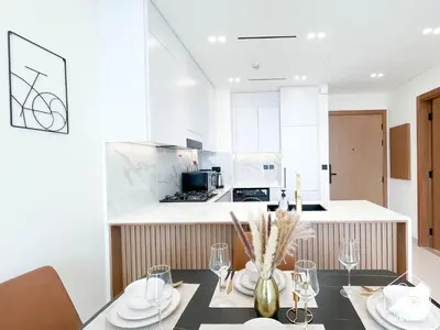 a kitchen with a table with plates and glasses at Bright and Modern 1BR Binghatti Amber with City View in Dubai