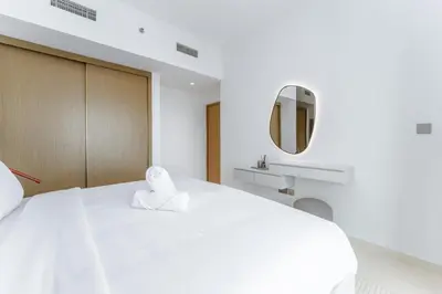 a bedroom with a large white bed with a mirror at Seafront 3BR with maid's - Grand Bleu by Elie Saab in Dubai