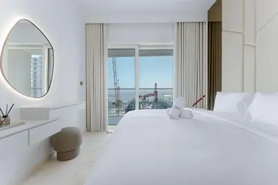 a white bedroom with a large bed and a mirror at Seafront 3BR with maid's - Grand Bleu by Elie Saab in Dubai