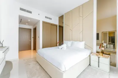a white bedroom with a large bed and a mirror at Seafront 3BR with maid's - Grand Bleu by Elie Saab in Dubai
