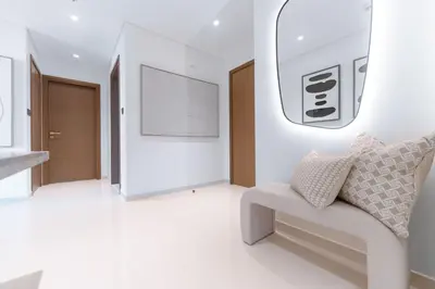 a white room with a chair and a mirror at Seafront 3BR with maid's - Grand Bleu by Elie Saab in Dubai