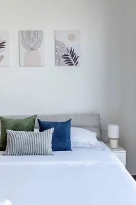 a white bed with blue and green pillows on it at GuestReady - Golden paradise in Dubai Hills in Dubai