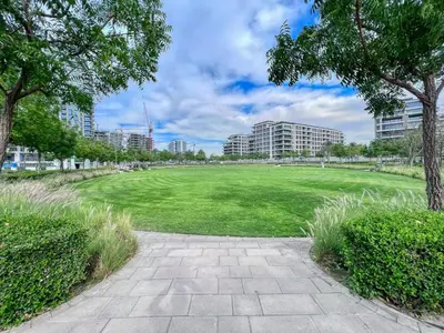 a large field with trees and buildings in the background at GuestReady - Golden paradise in Dubai Hills in Dubai