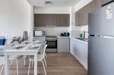a kitchen and living room with a white table and chairs at GuestReady - Golden paradise in Dubai Hills in Dubai