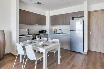 a kitchen with a white table and chairs and a refrigerator at GuestReady - Golden paradise in Dubai Hills in Dubai