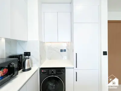 a white kitchen with a washer and dryer at Cozy Luxury l1BR Apartment in Binghatti Amber in Dubai