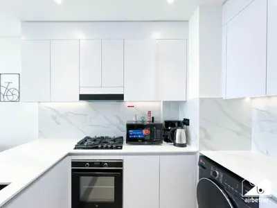 a white kitchen with a stove and a microwave at Cozy Luxury l1BR Apartment in Binghatti Amber in Dubai