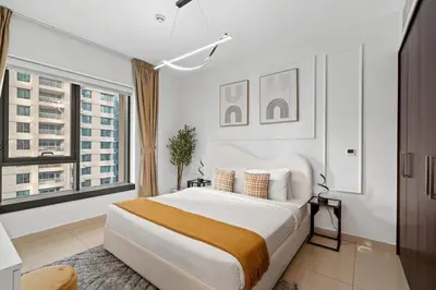 a white bedroom with a large bed and two windows at White House With Burj Views, Free Parking in Dubai