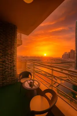 a balcony with tables and chairs and a sunset at Livincci - Luxury 1 Bed Apartment in JLT-10 in Dubai
