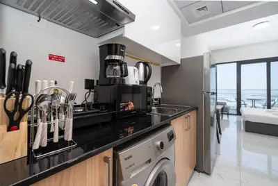 a kitchen with a stove top oven next to a dishwasher at Contemporary Studio Getaway in Jebel Ali in Dubai