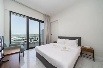 a bedroom with a large white bed and a balcony at Contemporary Studio Getaway in Jebel Ali in Dubai