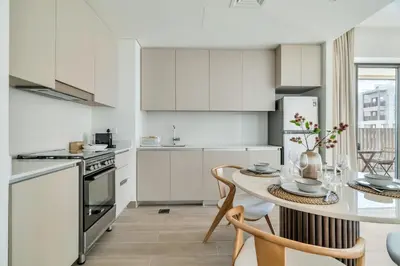 a kitchen with white cabinets and a table with chairs at 1-Bed at Creek Beach with Pool, Gym and Balcony in Dubai