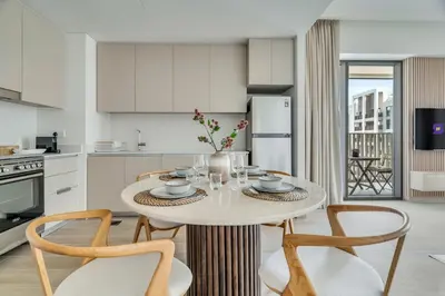 a white kitchen with a table and chairs in a room at 1-Bed at Creek Beach with Pool, Gym and Balcony in Dubai