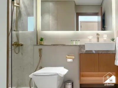a bathroom with a toilet and a sink and a mirror at Stylish 1 Bedroom with Pool Access in JVC in Dubai
