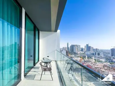 a balcony with chairs and a view of a city at Stylish 1 Bedroom with Pool Access in JVC in Dubai