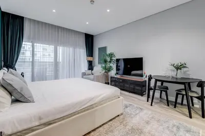 a bedroom with a bed and a table and a television at Knokey Cozy Studio Apartments in Business Bay in Dubai