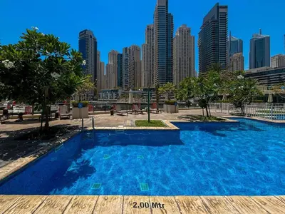 a blue swimming pool in front of a city skyline at Modern 1BR with Balcony and Marina Views in Al Majara 2 in Dubai