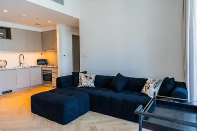 a living room with a blue couch and a kitchen at Creek Harbour Skyline Burj Khalifa & Sea View in Dubai