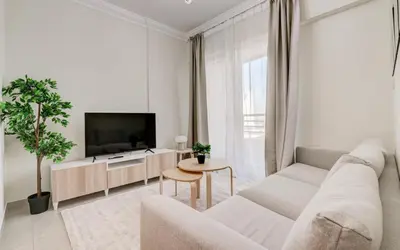 a white living room with a couch and a tv at Manchester Tower Dubai Marina in Dubai