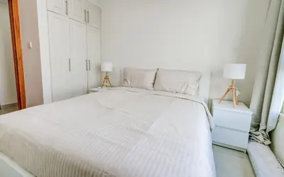 a white bed in a white bedroom with two lamps at Manchester Tower Dubai Marina in Dubai