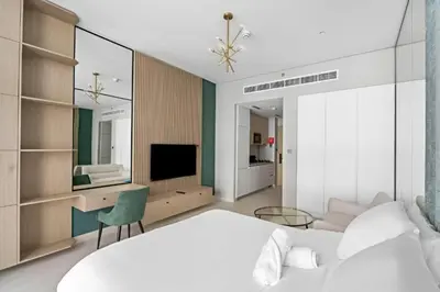 a bedroom with a white bed and a television at Modern Studio close to Marina with Balcony - 5 min walk from Metro in Dubai