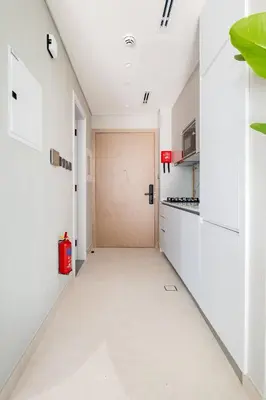 a hallway with a door in a kitchen with white cabinets at Modern Studio close to Marina with Balcony - 5 min walk from Metro in Dubai