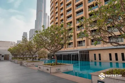 a swimming pool in front of a building with trees at Emmar fashion avenue Dubai mall in Dubai