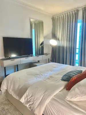 a bedroom with a bed with a desk and a television at Sky High luxury Stay in Dubai Marina ,with Marina View, High Floor, Modern Design, Pool Access by Stay Vista! Up to 6 Guests in Dubai