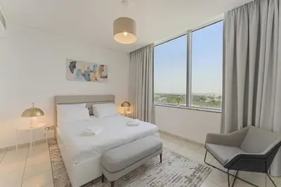 a white bedroom with a bed and a chair and window at Luxury 2BR Sky Gardens Appartment Downtown DIFC in Dubai