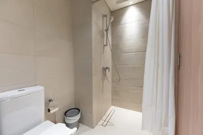 a bathroom with a shower and a white toilet at PVH - Cozy Studio in Azizi Riviera 43 in Dubai