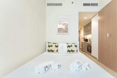a bedroom with a white bed with towels on it at PVH - Cozy Studio in Azizi Riviera 43 in Dubai