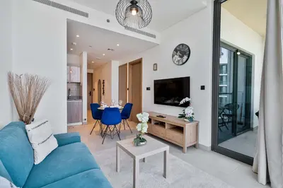 a living room with a blue couch and a table at PVH - Sobha Waves - Serene 1BR minutes to Downtown in Dubai