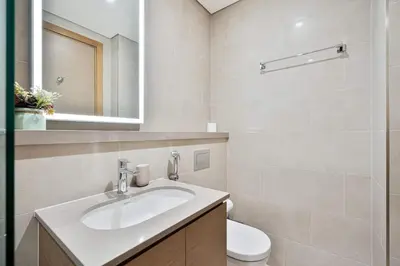 a bathroom with a sink and a toilet and a mirror at PVH - Sobha Waves - Serene 1BR minutes to Downtown in Dubai