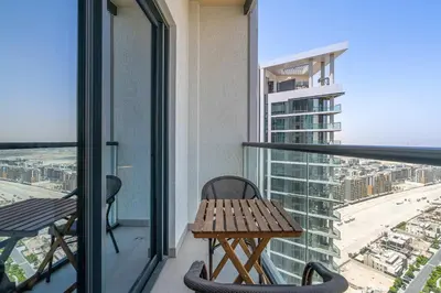 a balcony with a wooden table and chairs on a building at PVH - Sobha Waves - Serene 1BR minutes to Downtown in Dubai