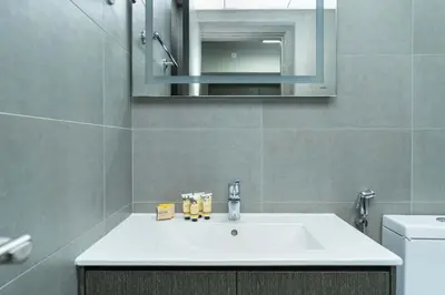 a bathroom with a sink and a mirror and a toilet at PVH - Homely Studio near Miracle Garden in Dubai