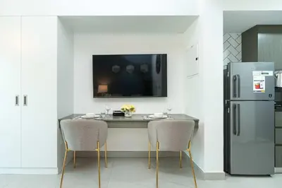 a kitchen with a table with two chairs and a refrigerator at PVH - Homely Studio near Miracle Garden in Dubai